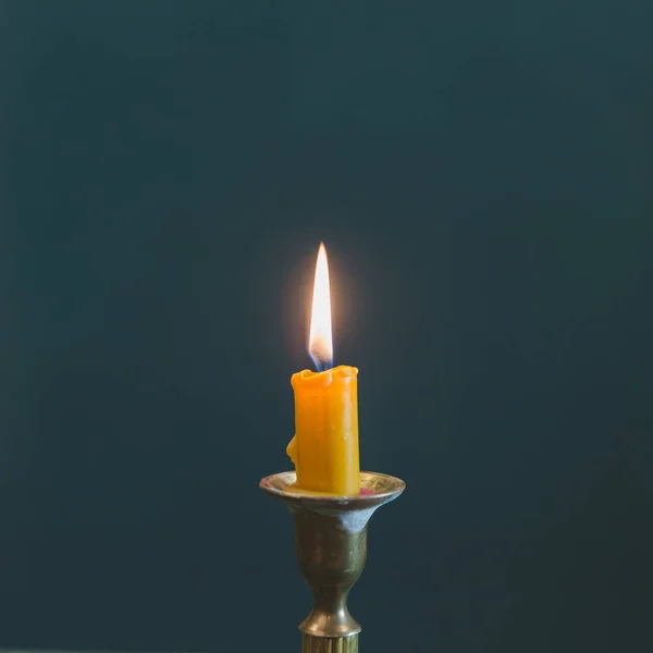 Burning candle, vintage bronze candlestick. Isolated dark blu ba — Stock Photo, Image