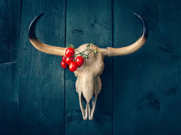 Buffalo skull with branch of red tomatoes. Country style, festiv