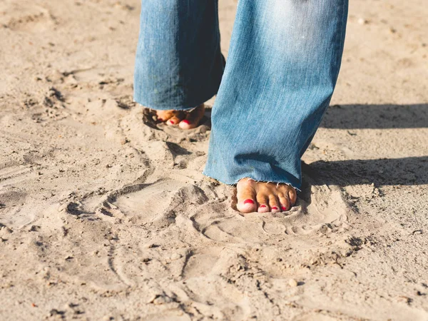 A woman in wide jeans walks on the sand barefoot. Freedom, trave — Stock Photo, Image