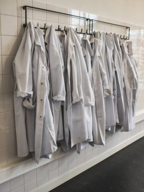 Duvarda asılı bir grup doktor ceketi. Soruşturma kavramı.