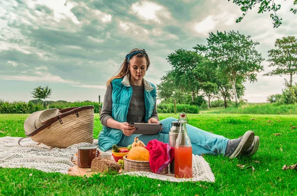 Young woman with tablet pc at a picnic on the nature In the countryside