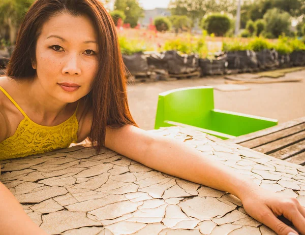 アジア系女性 40歳の女性が夏の庭に座ってカメラを見て — ストック写真