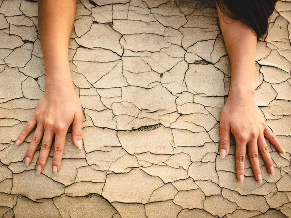 Kadının elleri çatlamış bir ola yüzeyinde uzanır..