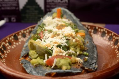 Meksika tlacoyos, mavi Mısır ile yapılan ve kızarmış fasulye veya bakla, guacamole, baharatlı sos, kişniş ve üst peynir ile Meksika tombik benzer ile dolu bir tabak