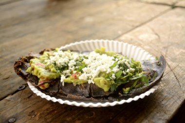 Meksika tlacoyos, mavi Mısır ile yapılan ve kızarmış fasulye veya bakla, guacamole, baharatlı sos, kişniş ve üst peynir ile Meksika tombik benzer ile dolu bir tabak