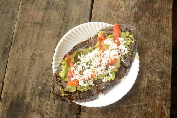 Meksika tlacoyos, mavi Mısır ile yapılan ve kızarmış fasulye veya bakla, guacamole, baharatlı sos, kişniş ve üst peynir ile Meksika tombik benzer ile dolu bir tabak