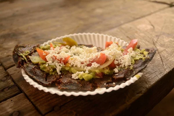 Mexikói tlacoyos, egy tál készült kék kukorica és tele sült bab vagy a lóbab, hasonlít a mexikói gordita, guacamole, fűszeres mártással, koriander és sajttal a tetején — Stock Fotó