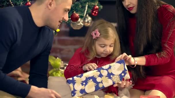 Батьки допомагають доньці відкрити подарунок на Різдво — стокове відео