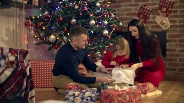 I genitori aiutano la figlia ad aprire un regalo a Natale — Video Stock