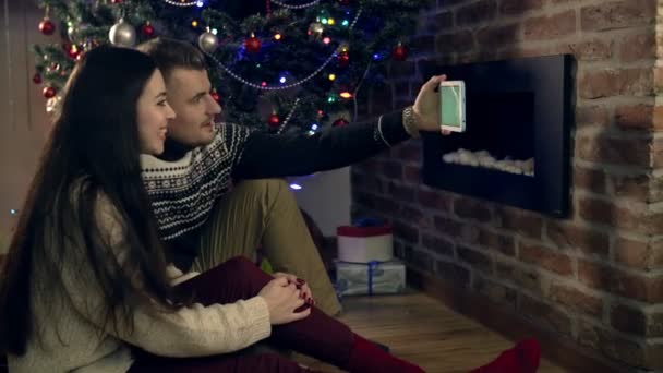 Pár se shromáždili kolem vánočního stromu, pomocí tablet — Stock video