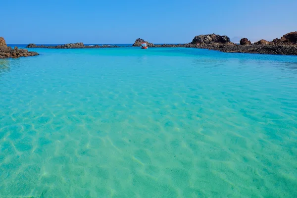 Laguna con agua azul transparente y un barco en Fuerteventura , — Foto de Stock