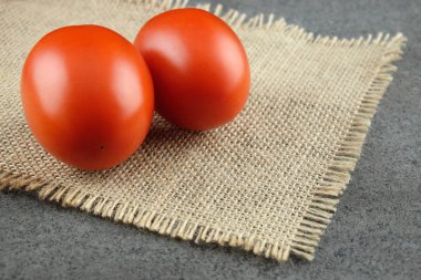 Bir çuval bezi üzerinde iki kırmızı domates.