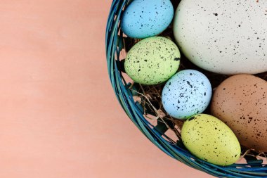 Paskalya renkli bıldırcın yumurtası soluk pembe backgro üzerinde mavi sepet içinde