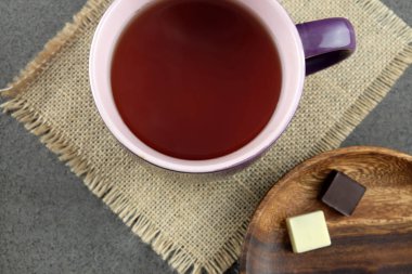 Fincan çay ve çikolata ahşap plaka üzerinde iki adet.