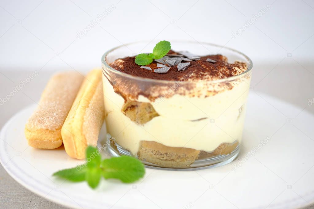 Tiramisu, traditional italian dessert in a glass on light background.
