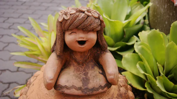 Pottery garden figure of a laughing girl in an exotic park in Thailand.