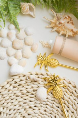 Deniz kabukları, kokteyle karşılık altın ananas ve hasır yatağa güneş kremi..