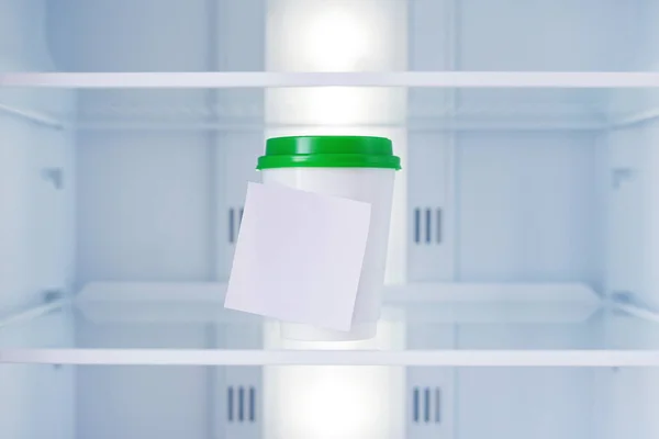 Disposable cup for soup in an empty refrigerator with sticker.