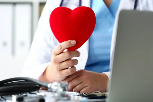 Female medicine doctor hands holding red toy heart