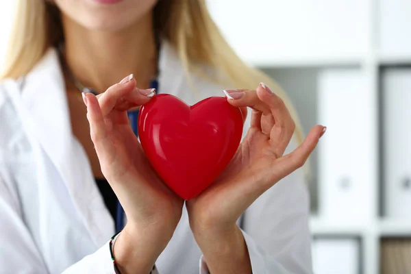 Vrouwelijke geneeskunde arts handen houden en die betrekking hebben op rode speelgoed hart — Stockfoto