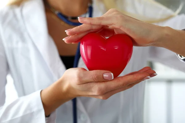 Kvinnliga medicine doktor händer hålla och som täcker röda leksak hjärta — Stockfoto