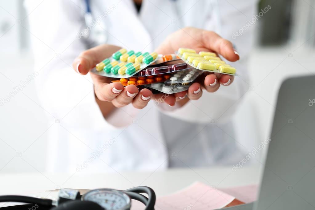 Female doctor hand holding pack of different tablet blisters