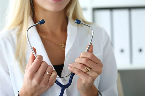 Mujer médico manos sosteniendo estetoscopio delante del pecho —  Fotos de Stock