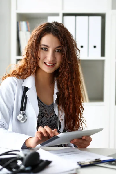 Улыбающаяся женщина-врач держит в руках планшетный компьютер — стоковое фото