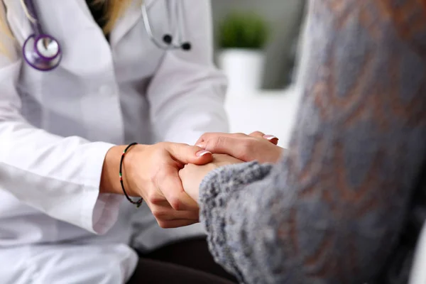 Amigable médico femenino sostiene paciente de la mano en el consultorio durante la recepción —  Fotos de Stock