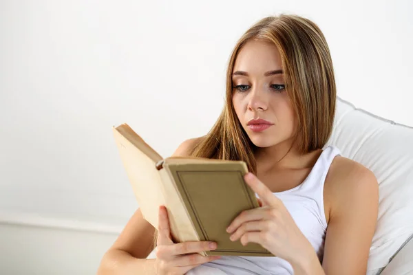 Young beautiful blonde woman lying in bed reading old book — Stock Photo, Image