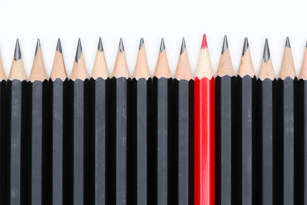 Червоний олівець, що виділяється з натовпу багатьох ідентичних чорних копів — стокове фото
