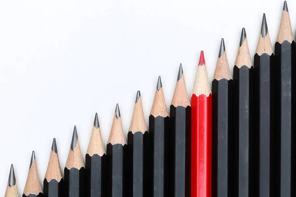 Червоний олівець, що виділяється з натовпу багатьох ідентичних чорних копів — стокове фото