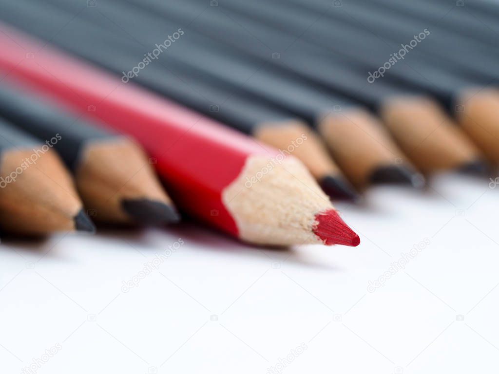 Red pencil standing out from crowd of plenty identical fellows 