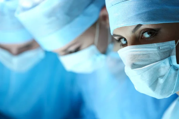 Three surgeons at work operating in surgical theatre — Stock Photo, Image