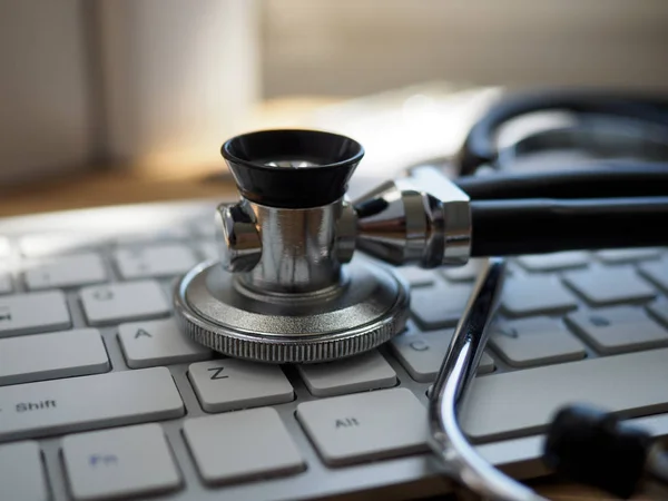 Stethoscope head lying on silver keyboard closeup — Stock Photo, Image