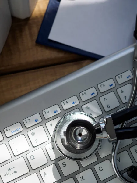 Stethoscope head lying on silver keyboard closeup — Stock Photo, Image