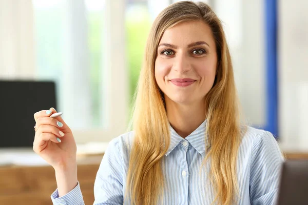 Menina sorridente bonita no local de trabalho segurar caneta de prata — Fotografia de Stock