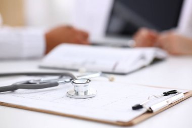 Stetoskop baş aracı closeup doktor ofisinde arka planda çalışma sırasında eklenecek kısaltıldı kardiyogram yatan. Nabız ölçümü, sağlıklı yaşam, therapeutist sınav hasta, fiziksel kavramı