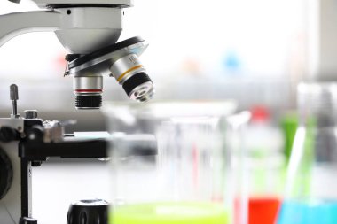 Mikroskop şişelerin arasında okulda kimya laboratuvarında duruyor.