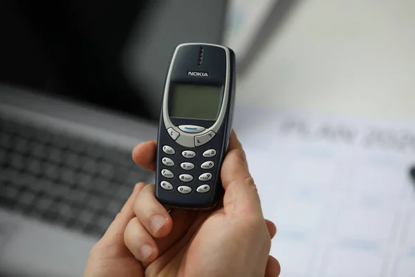 Nokia 3310 cep telefonunu tutan erkek kol.