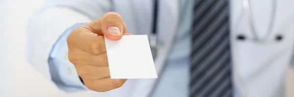 Мужской врач держит и дает белую пустую визитную карточку — стоковое фото