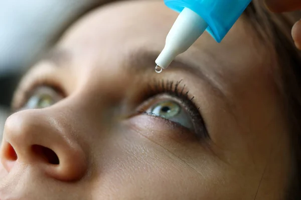 Vrouw zetten vloeibare druppels in haar oog oplossen visie probleem — Stockfoto