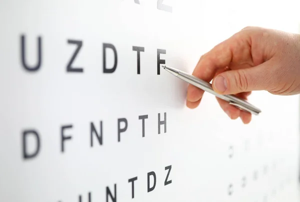 Серебряная шариковая ручка, указывающая на букву в таблице проверки зрения — стоковое фото