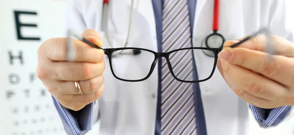 Médico masculino mãos dando par de óculos pretos — Fotografia de Stock
