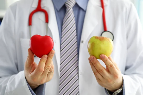 Male doctor holding red heart and apple closeup — 스톡 사진