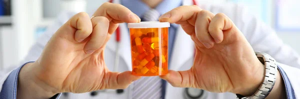 Male medicine doctor hand holding and offering to patient jar of pills Stock Picture