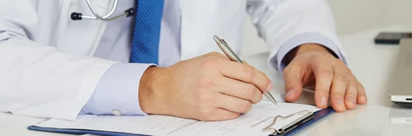Médico de medicina masculina mãos preenchendo o formulário de registro do paciente com caneta de prata — Fotografia de Stock