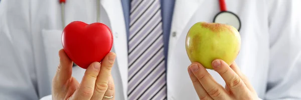 Male doctor holding red heart and apple closeup — Stock Photo, Image