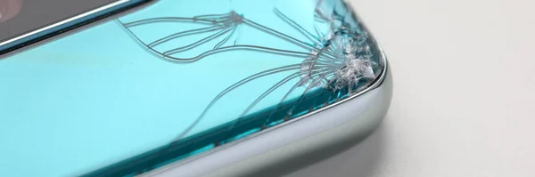 Modern smartphone lying at table with crack in corner — Stok fotoğraf