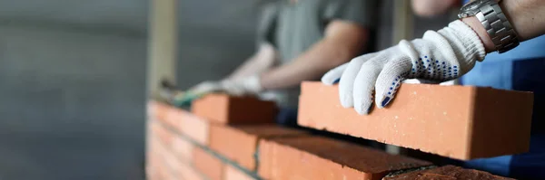 Twee arbeiders maken rode bakstenen muur op bouwplaats — Stockfoto